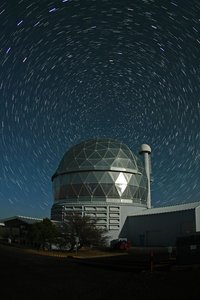Large telescope dome under a night sky with circular star trails