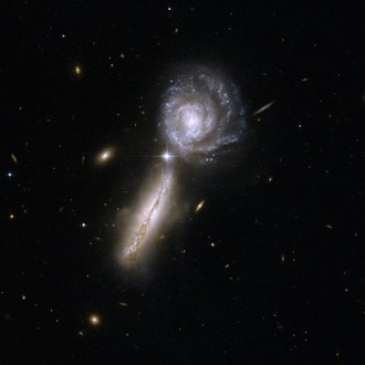Zwei nah beieinander stehende Galaxien, eine von der Seite gesehen, die andere von oben. Bei dieser ist eine Spiralstruktur erkennbar.