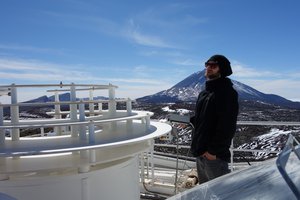 Junger Mann mit Sonnenbrille und Mütze, im Hintergrund ein großer Berg und blauer Himmel